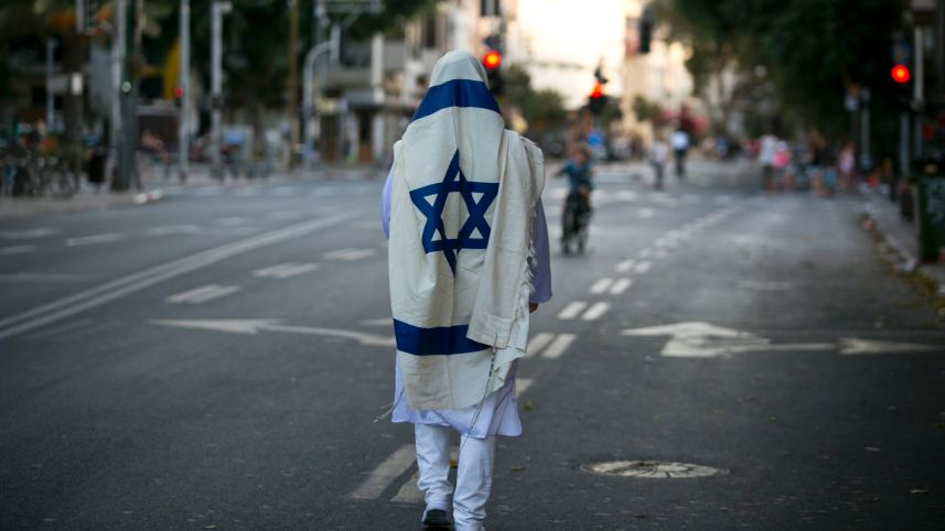 A man wrapped in a prayer shawl walks through a deserted Tel Aviv street on Yom Kippur, Israel, 2016. Credit: Ofer Vaknin