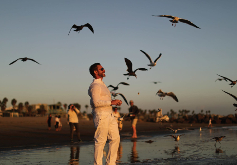 A MAN throws bread crumbs into the Pacific Ocean during the Tashlich prayer, a Rosh Hashana ritual to symbolically cast away sins, last week.. (photo credit:REUTERS)